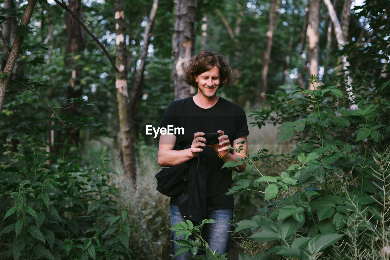 Young man photographing through camera in forest