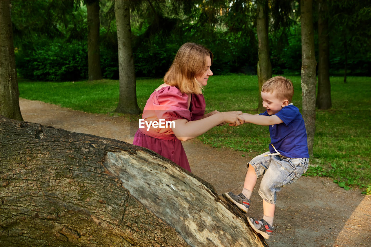 Full length of mother and daughter on tree against plants