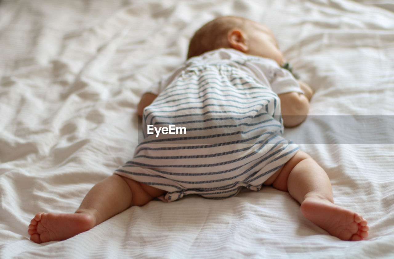 Midsection of baby sleeping on bed