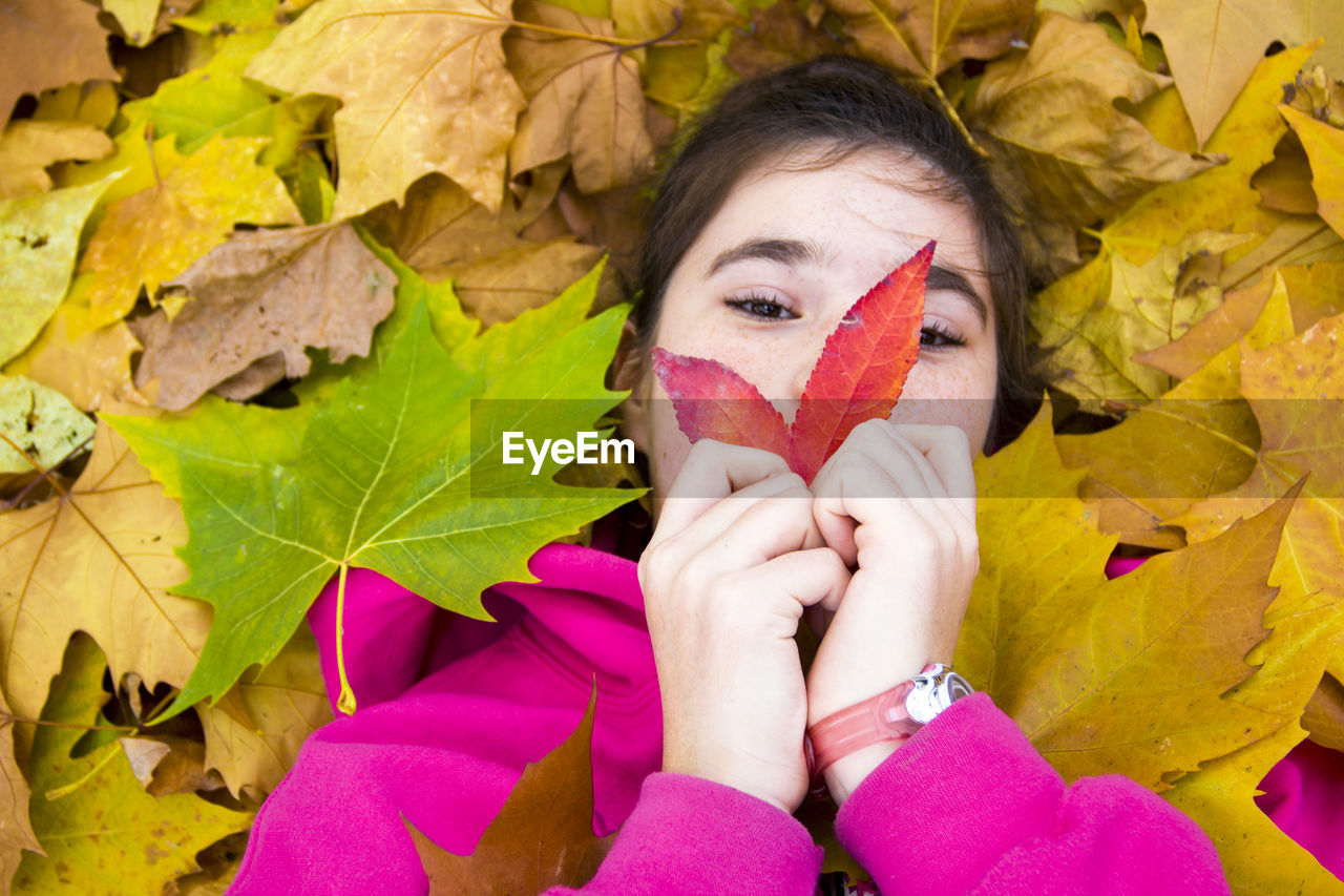 Portrait of girl with autumn leaves lying down outdoors