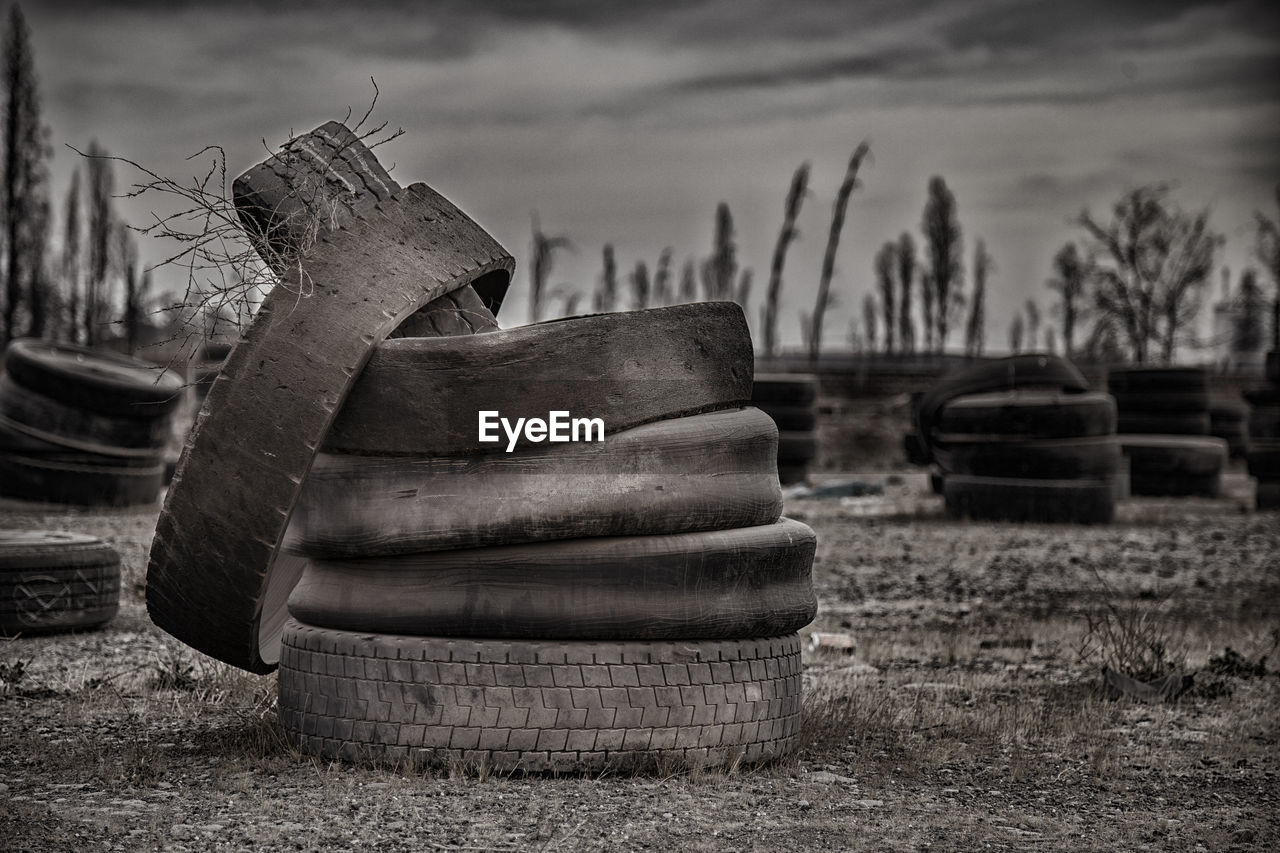 Obsolete tires on field against sky
