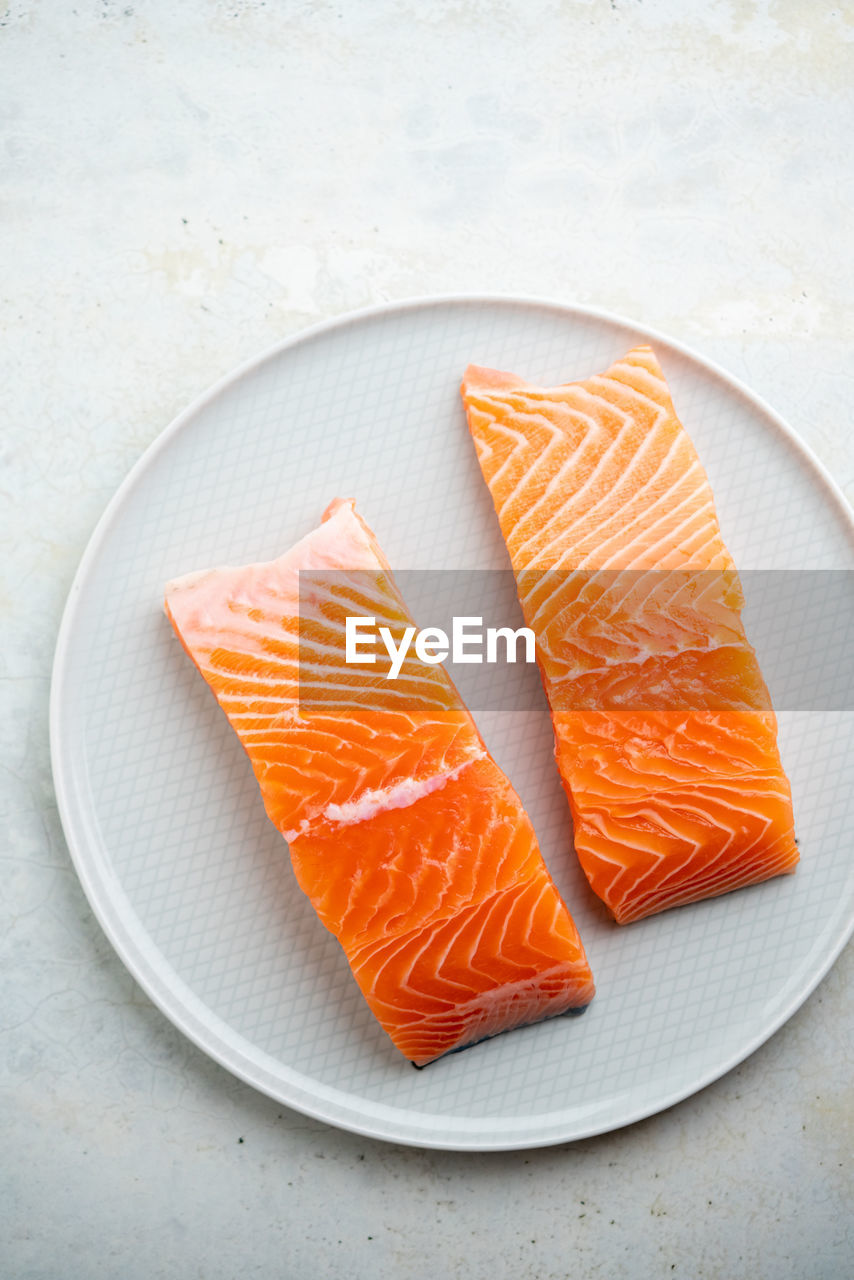 food, food and drink, fish, healthy eating, orange, freshness, wellbeing, no people, salmon-like fish, plate, seafood, salmon, orange color, raw food, high angle view, produce, slice, indoors, studio shot, dish, close-up, cuisine, directly above