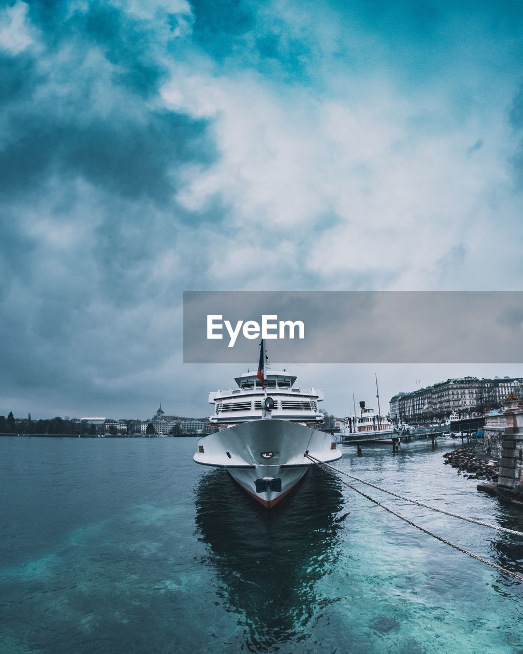 SHIP MOORED IN HARBOR AGAINST SKY