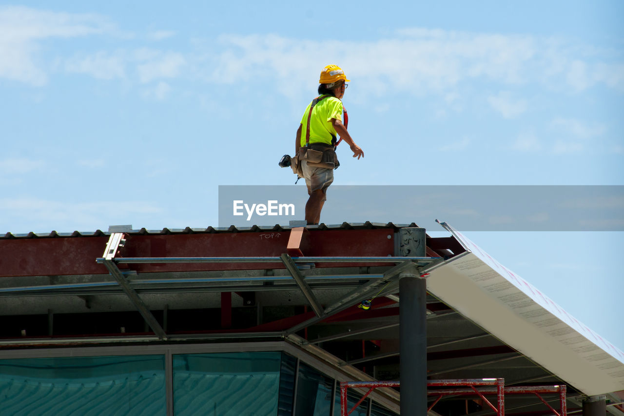 LOW ANGLE VIEW OF BOY STANDING ON ROOF