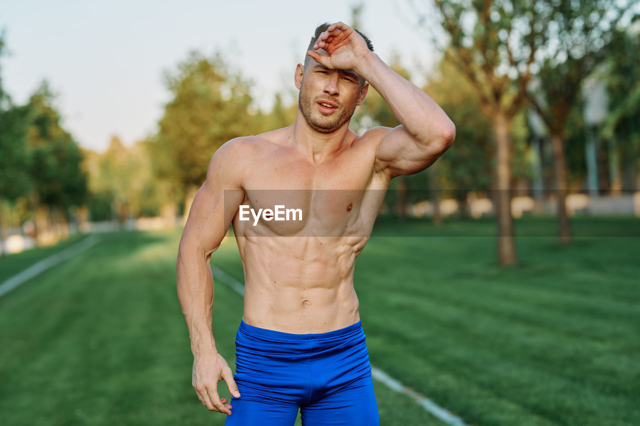 portrait of shirtless young man standing outdoors