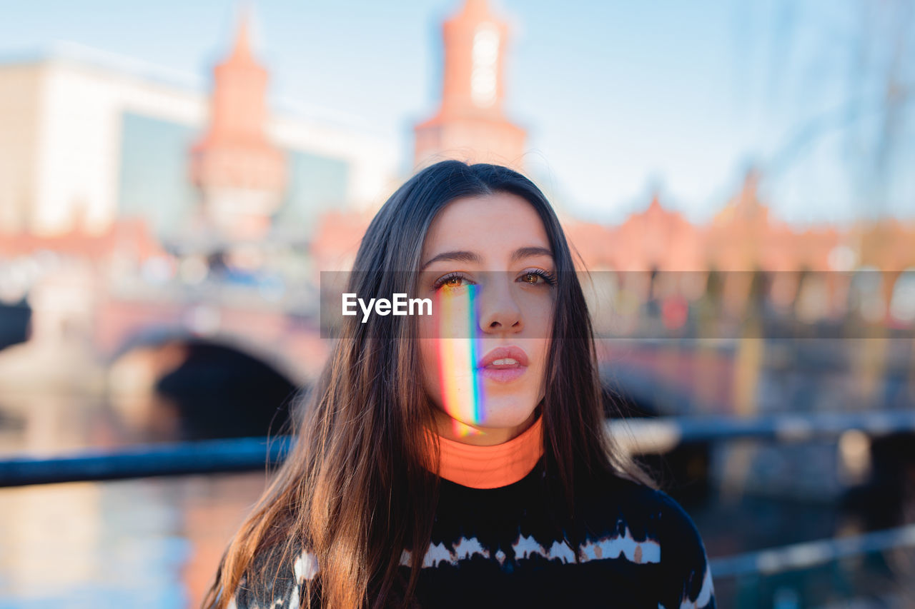 Portrait of young woman with spectrum of face in city