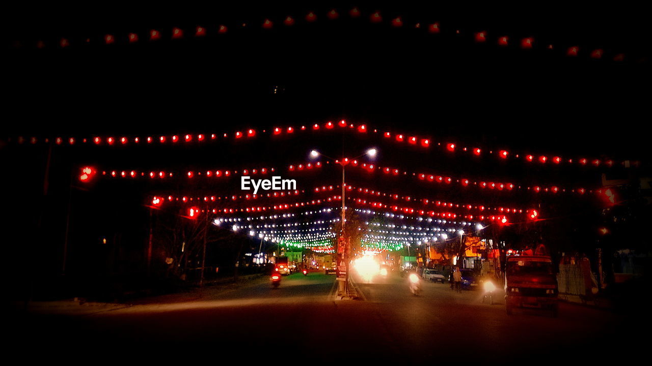 Vehicles moving on street with illuminated decoration at night