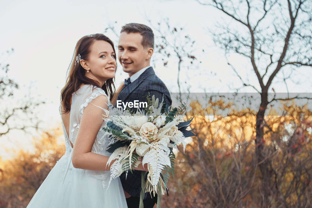 portrait of bride and bridegroom holding bouquet