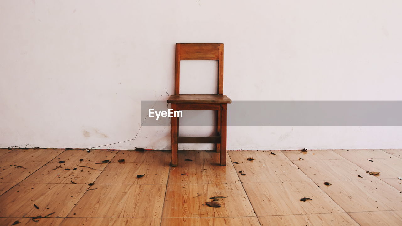 CLOSE-UP OF CHAIR ON HARDWOOD FLOOR AGAINST WALL