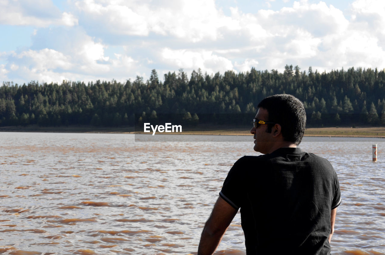 REAR VIEW OF MAN STANDING IN WATER