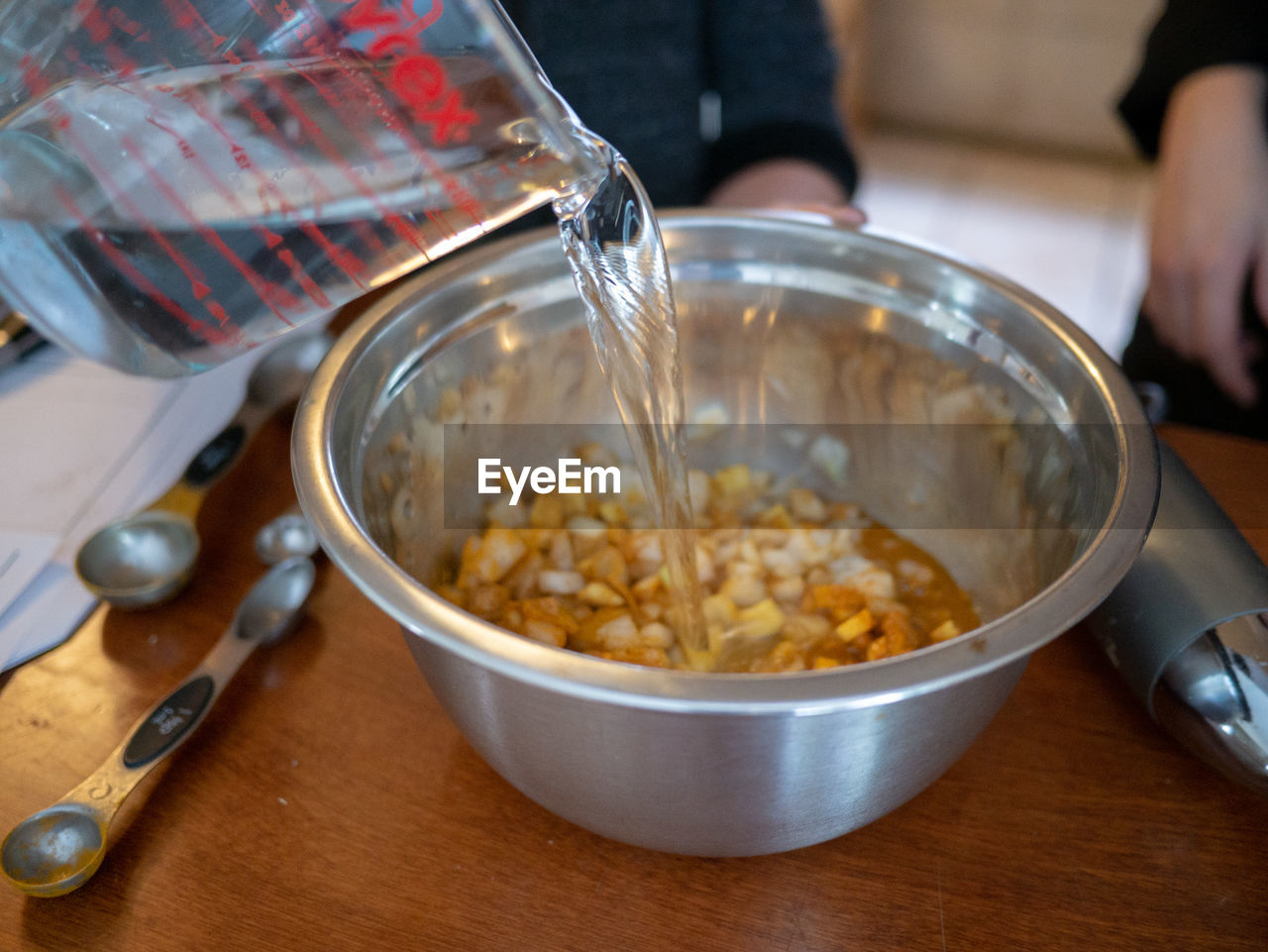 Midsection of person preparing food in bowl on table