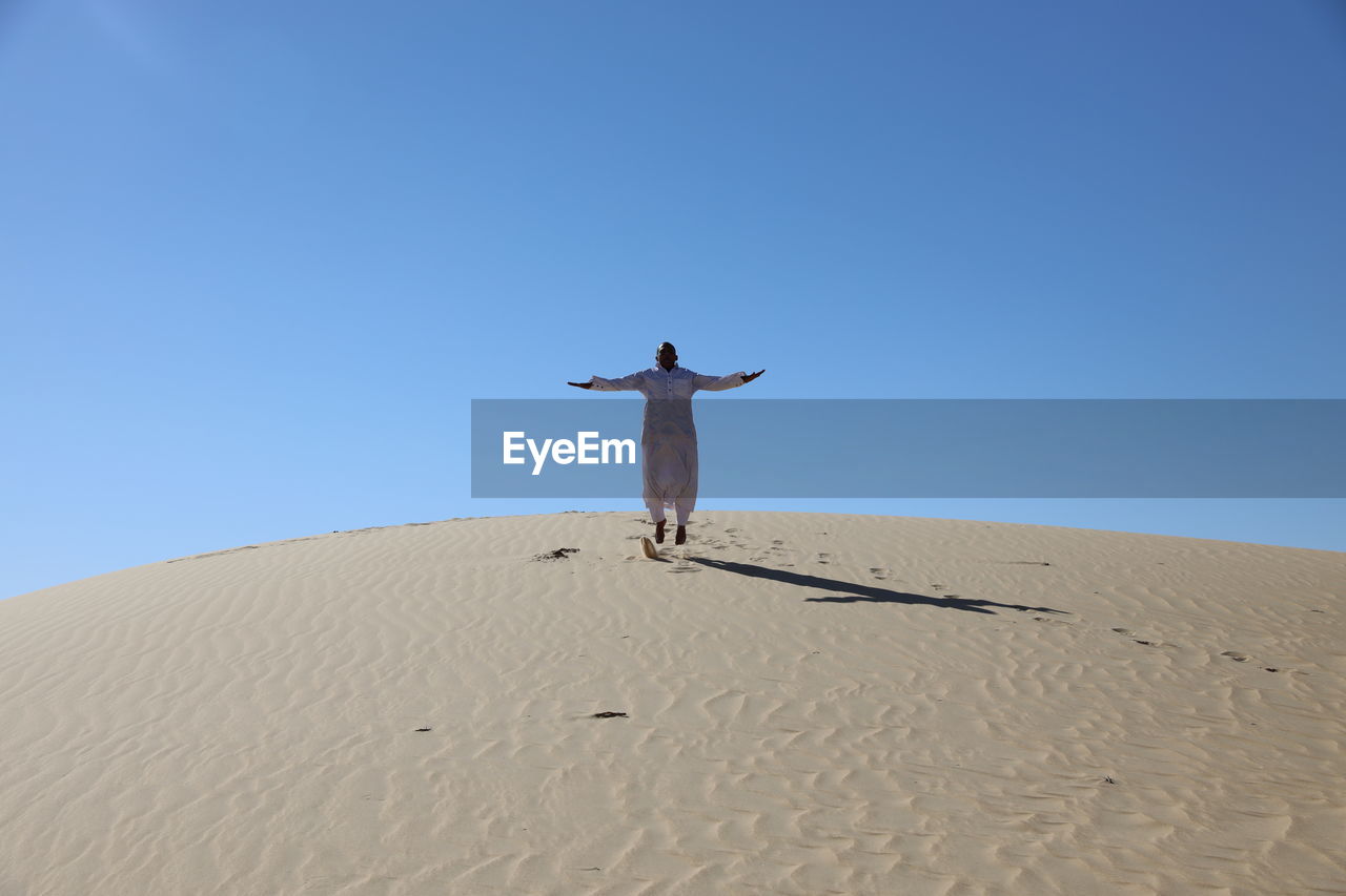 Low angle view of person jumping sand dune