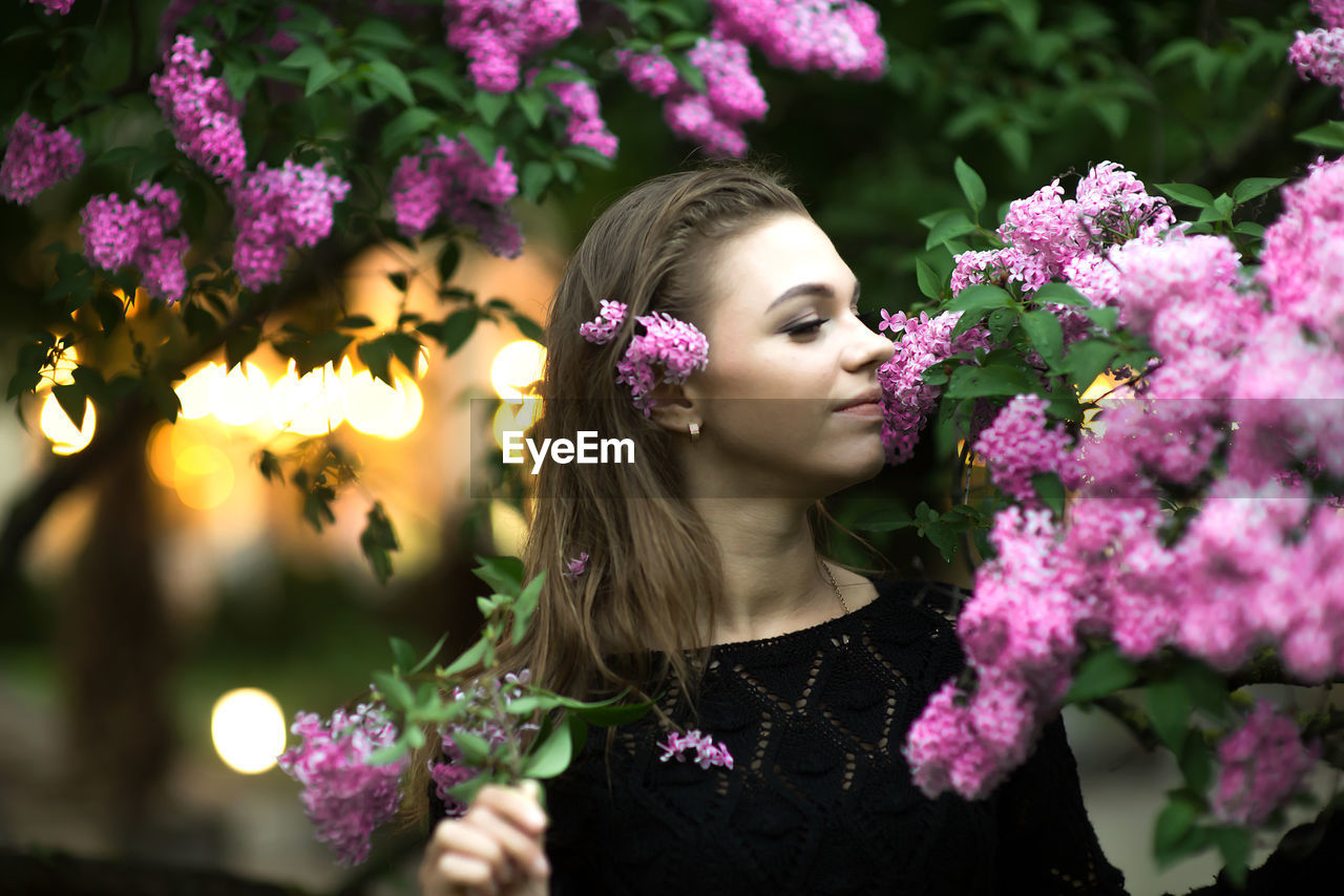 Young woman by purple flowers on branches