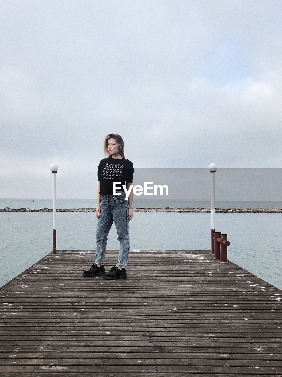 Rear view of woman walking on pier over sea against sky