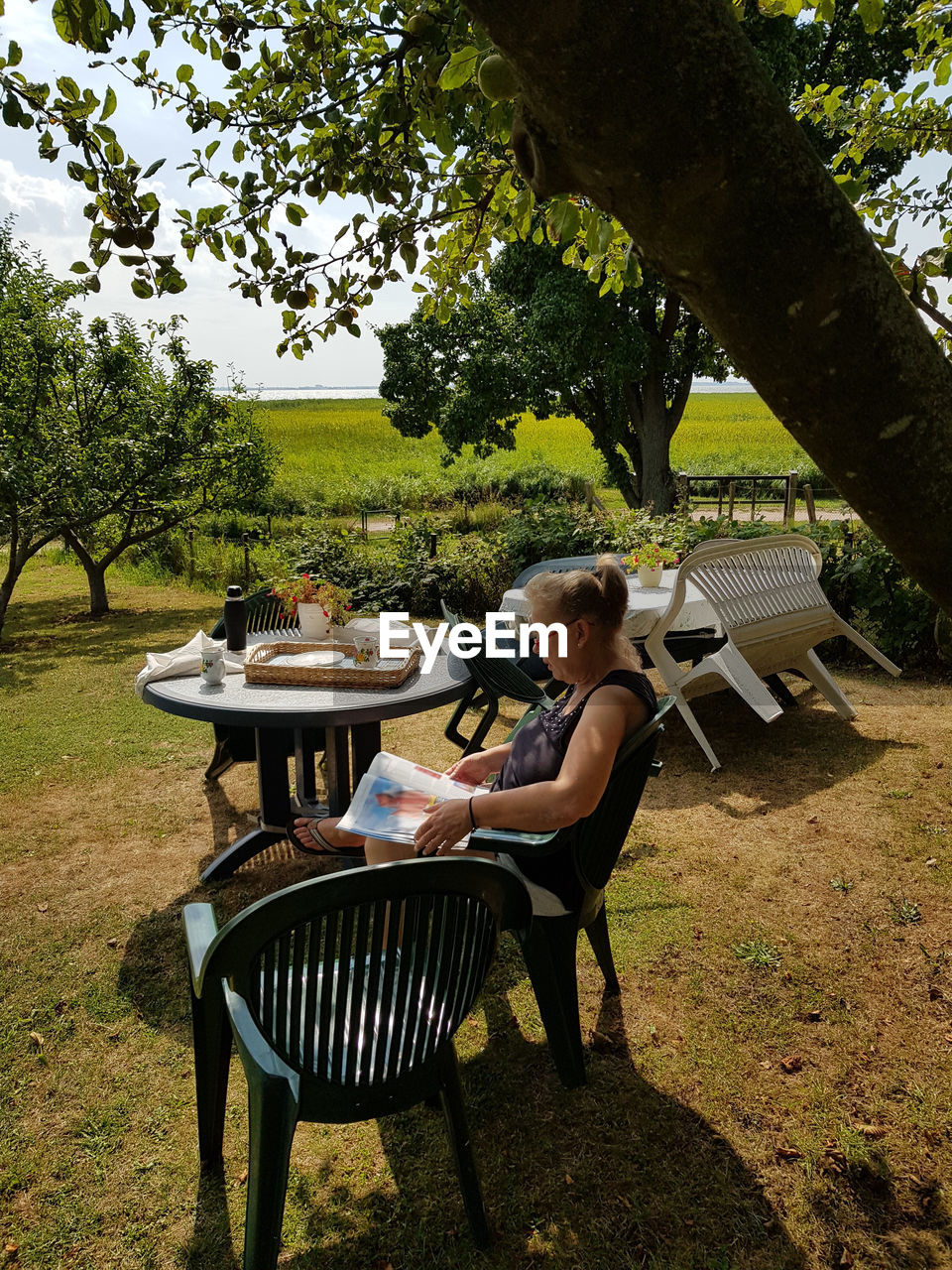 WOMAN SITTING ON TABLE IN YARD