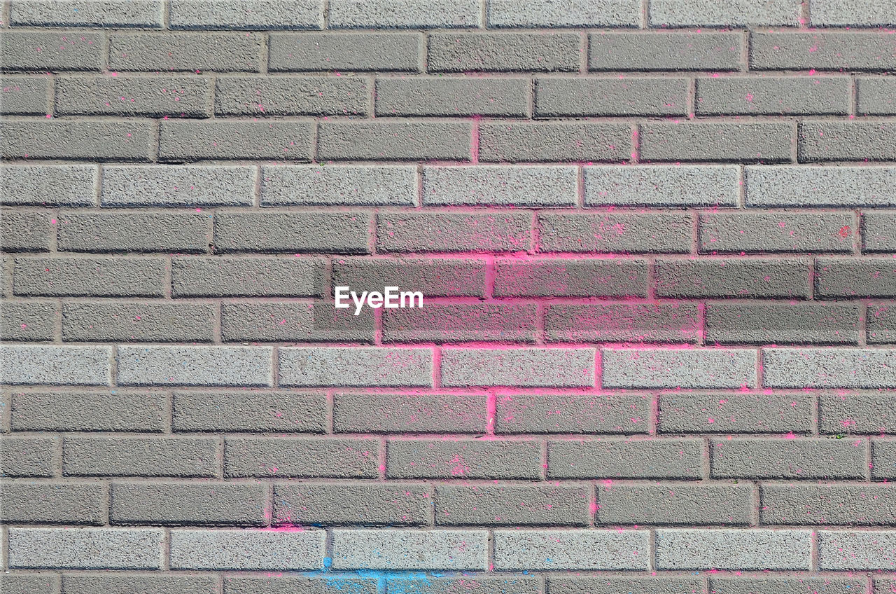 FULL FRAME SHOT OF BRICK WALL WITH PINK PATTERN ON FLOOR