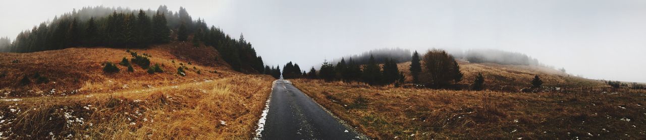 Panoramic shot of empty road on field against sky during foggy weather