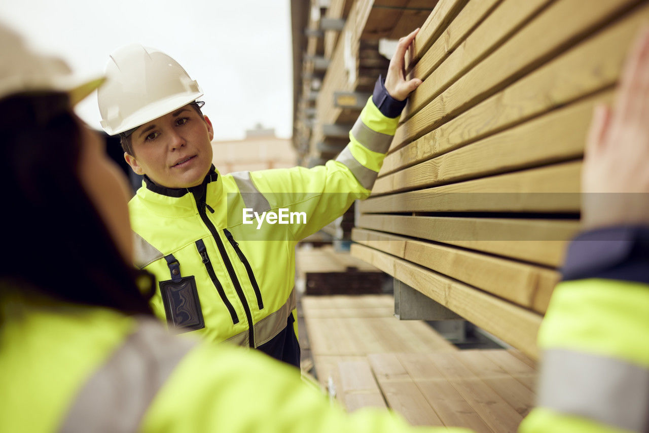 Multiracial female workers discussing over planks stacked at industry