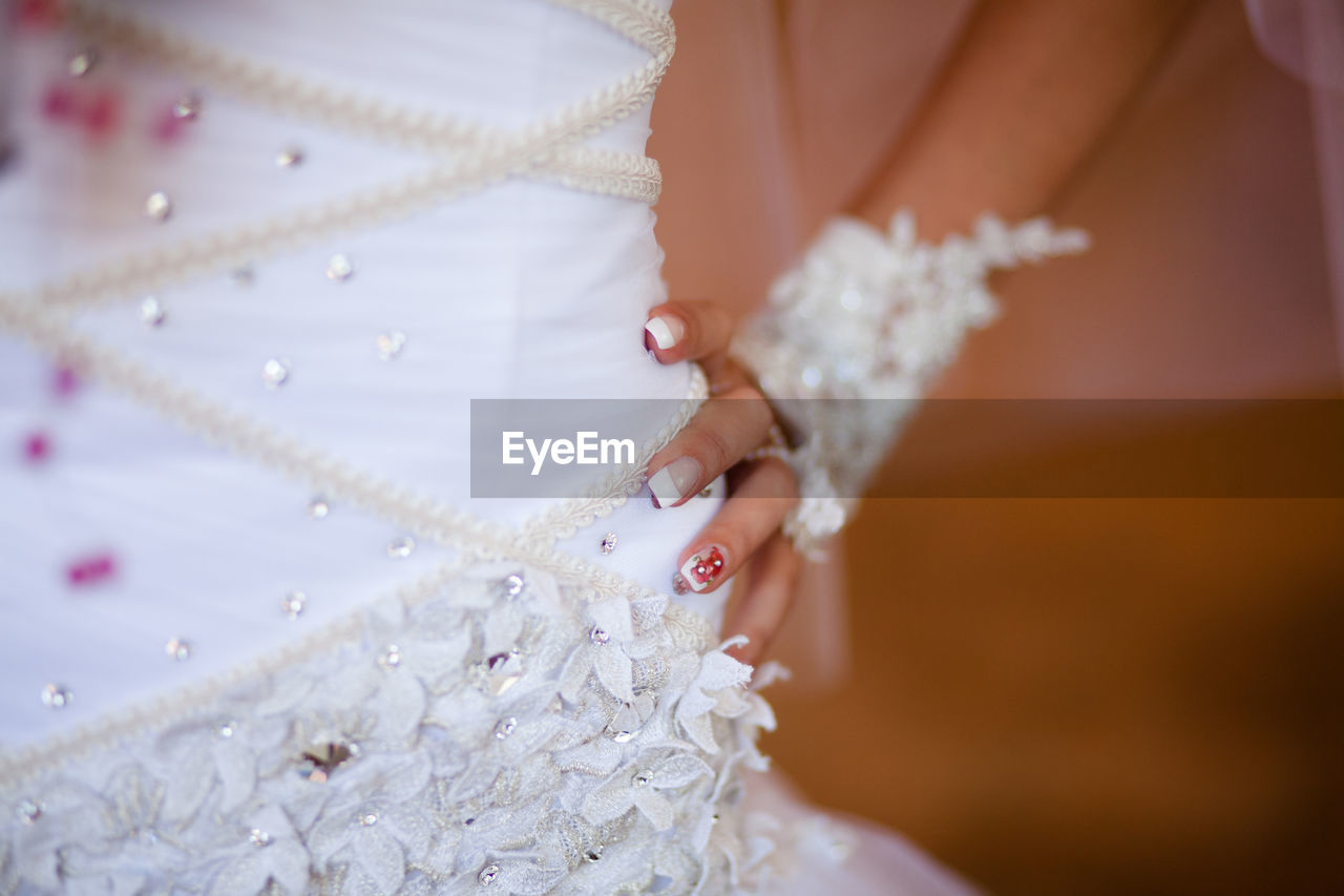 wedding dress, wedding, celebration, bride, newlywed, dress, adult, women, event, bridal clothing, life events, gown, jewelry, clothing, one person, fashion, white, pink, midsection, married, wedding ceremony, hand, ceremony, indoors, elegance, fashion accessory, female, close-up, pearl jewelry, necklace, love, bracelet, lace - textile, young adult, ring, formal wear, tradition, traditional clothing, selective focus