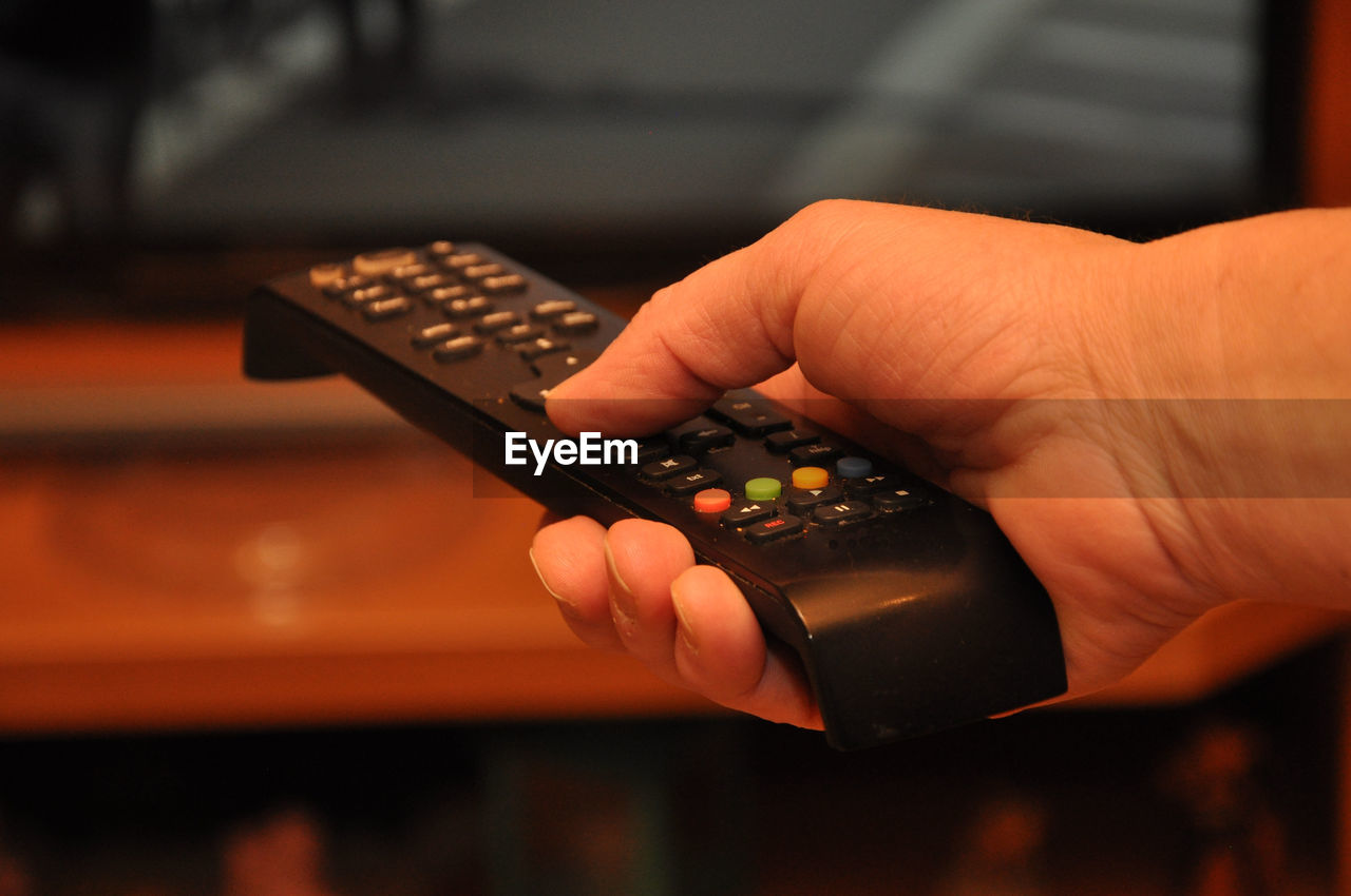 Close-up of cropped hand holding remote control