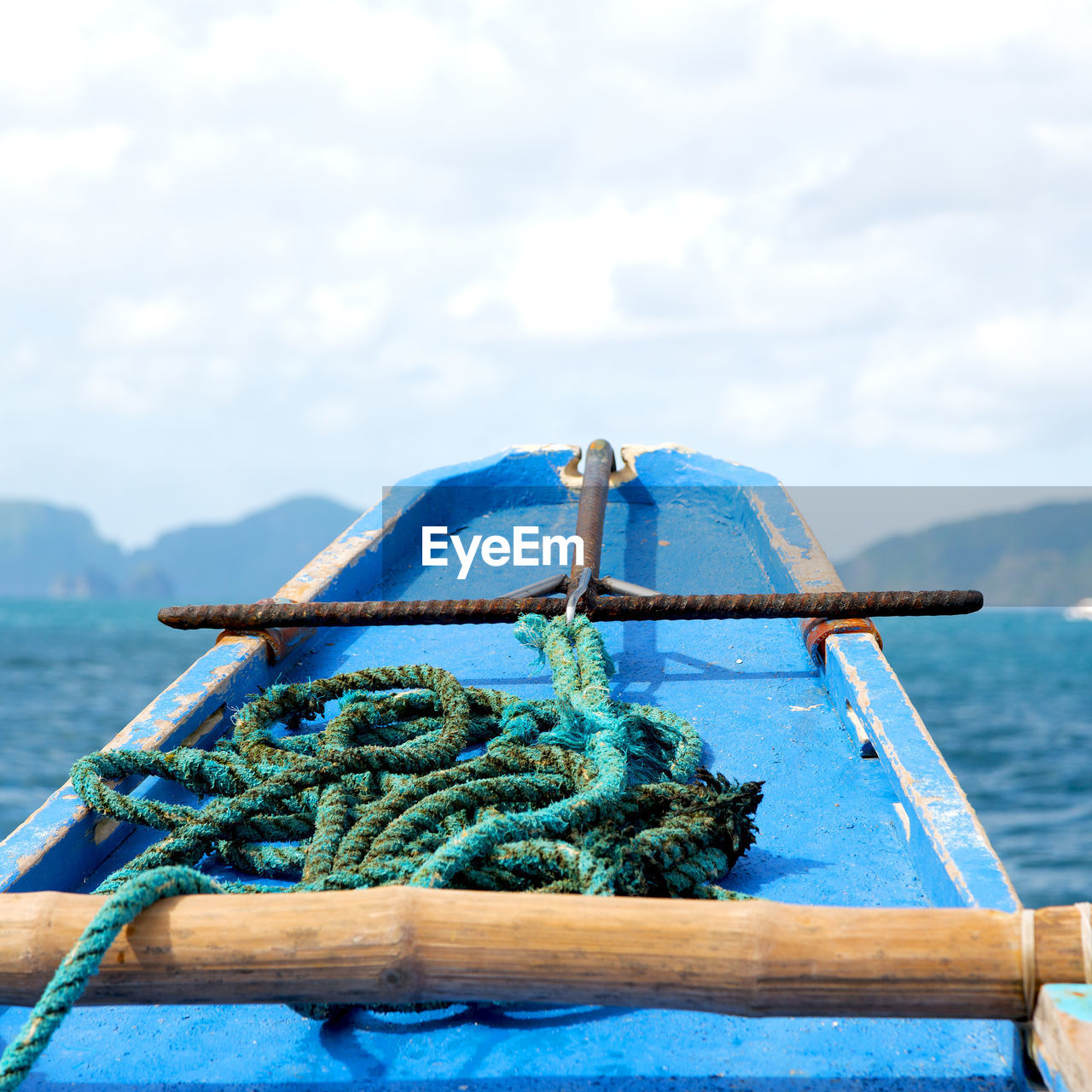 CLOSE-UP OF ROPE TIED ON WOODEN POST AGAINST SEA