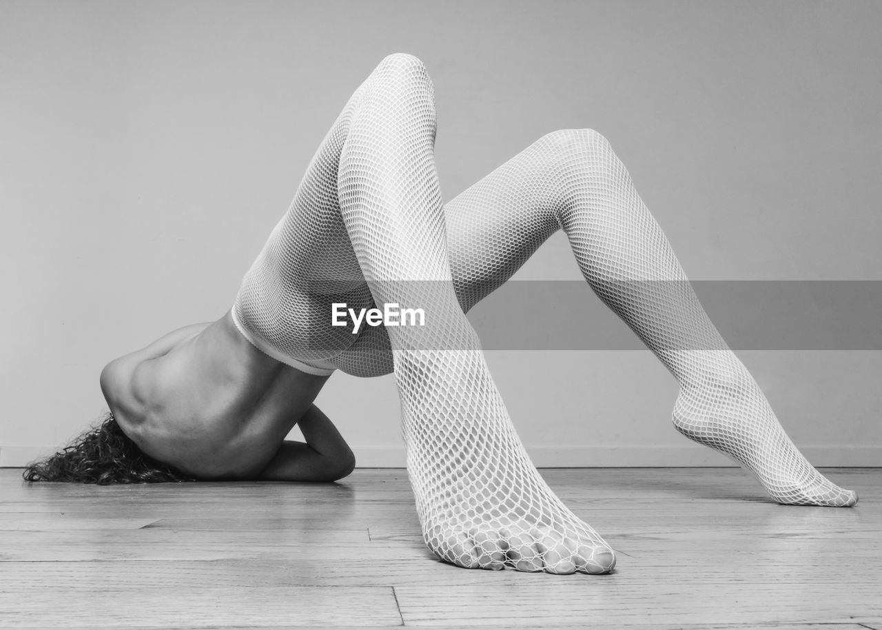 Low section of woman sitting on hardwood floor