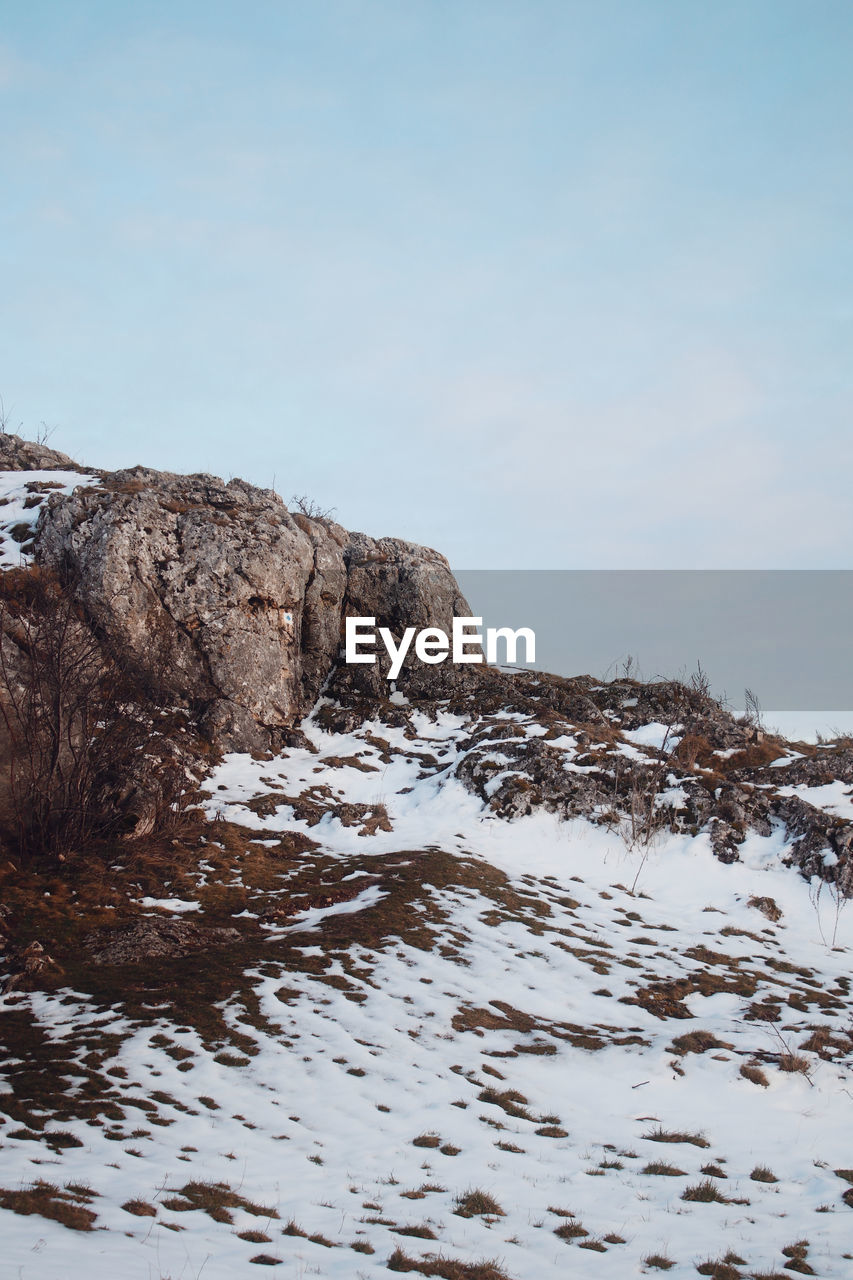 SNOW COVERED ROCKS AGAINST CLEAR SKY