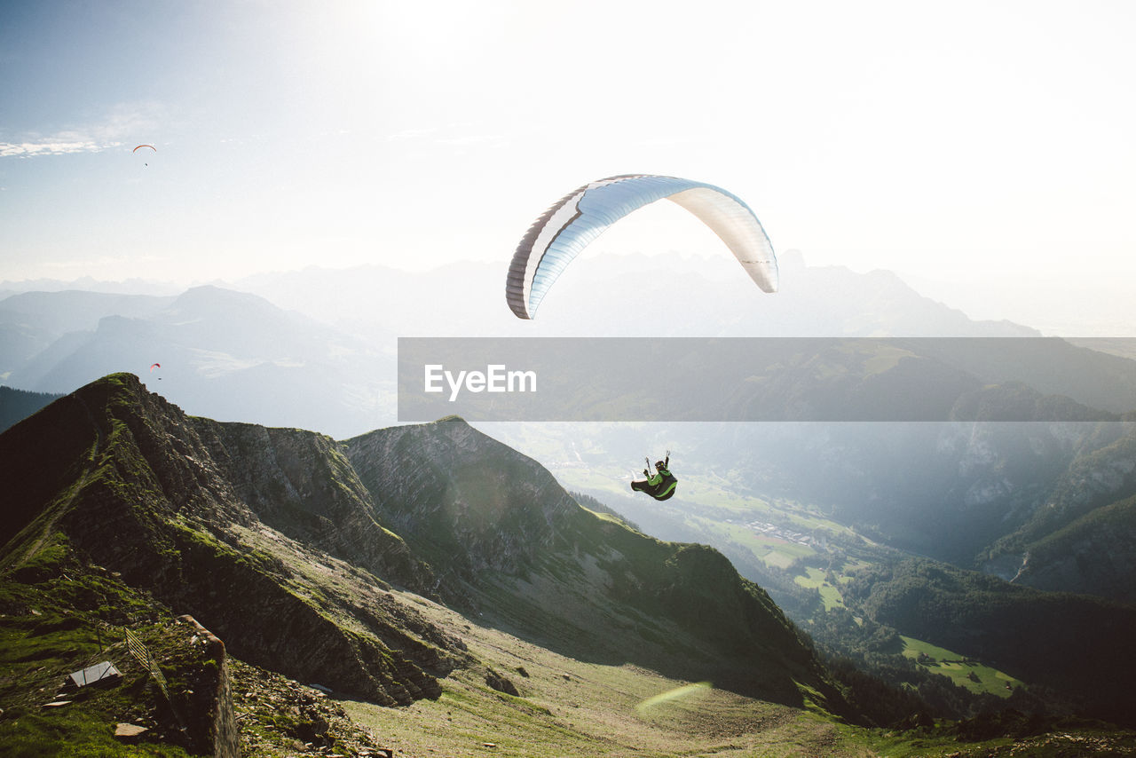 Man paragliding over mountains against sky