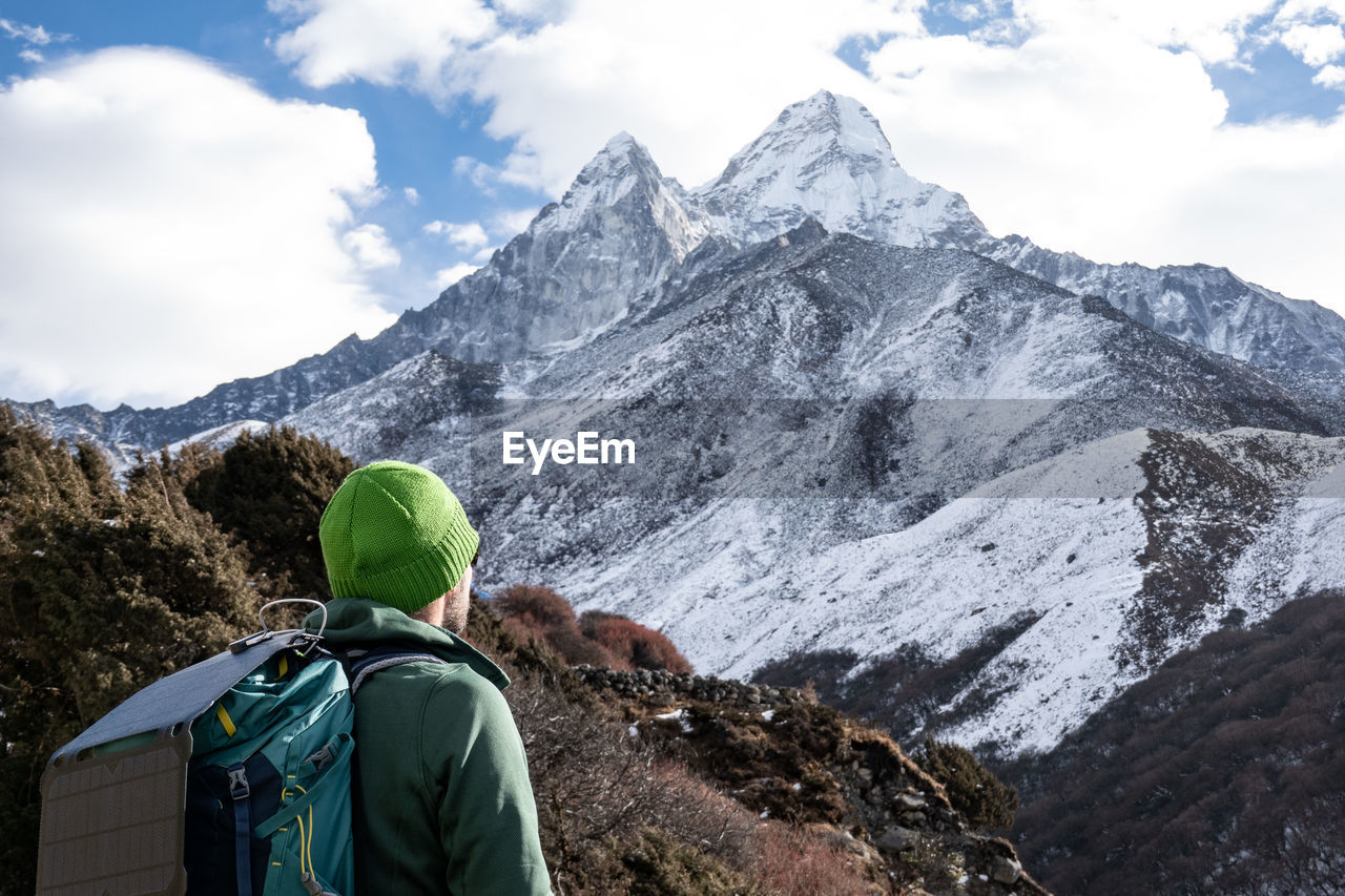 Rear view of man looking at mountains during winter