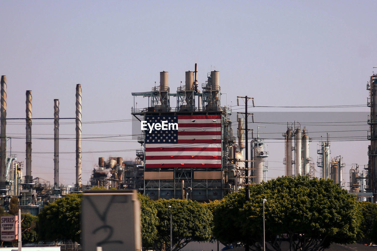 American flag on industry building against clear sky