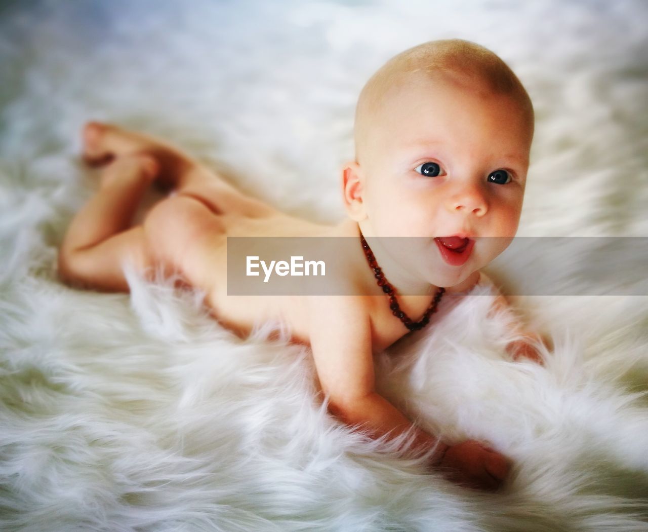 High angle view of naked baby lying on fur rug at home