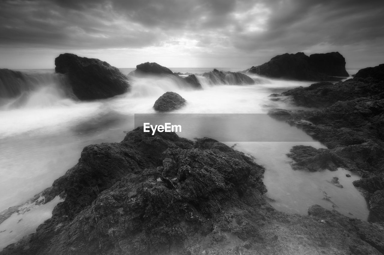 ROCKS IN SEA AGAINST SKY