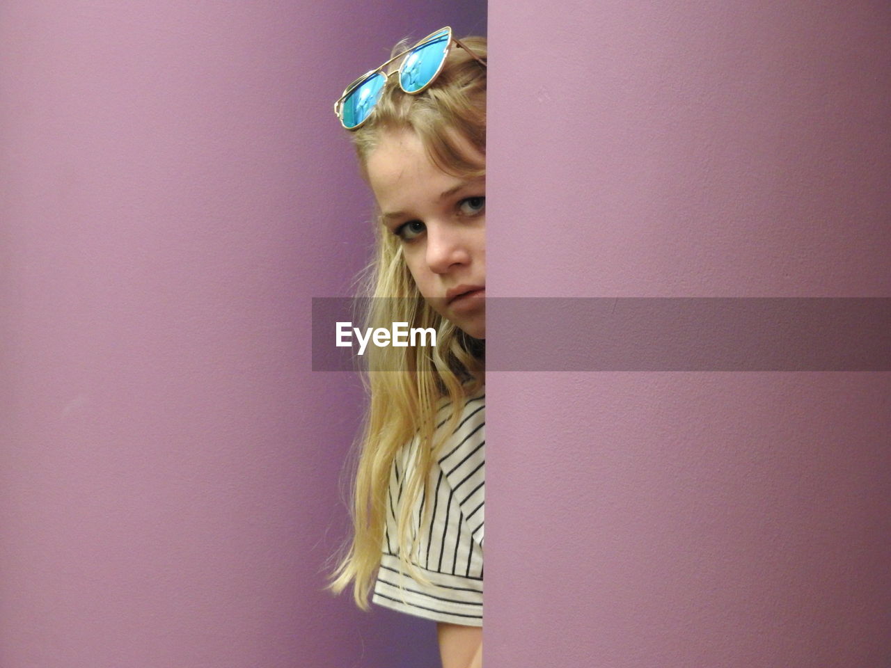 Portrait of girl hiding behind wall