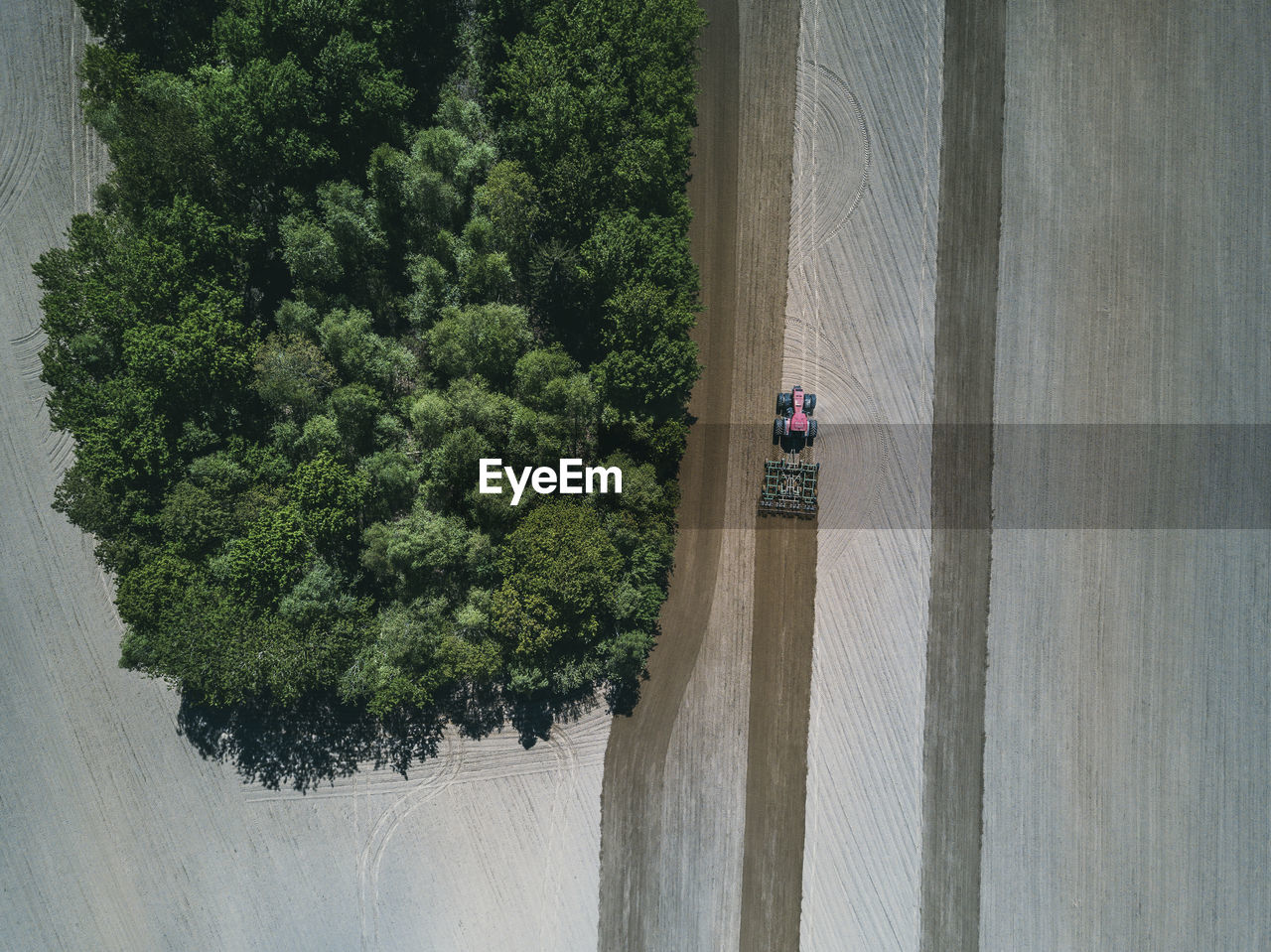 Aerial view of tractor in agricultural field by trees