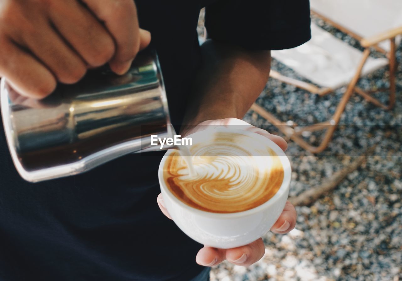 Midsection of man holding coffee on table