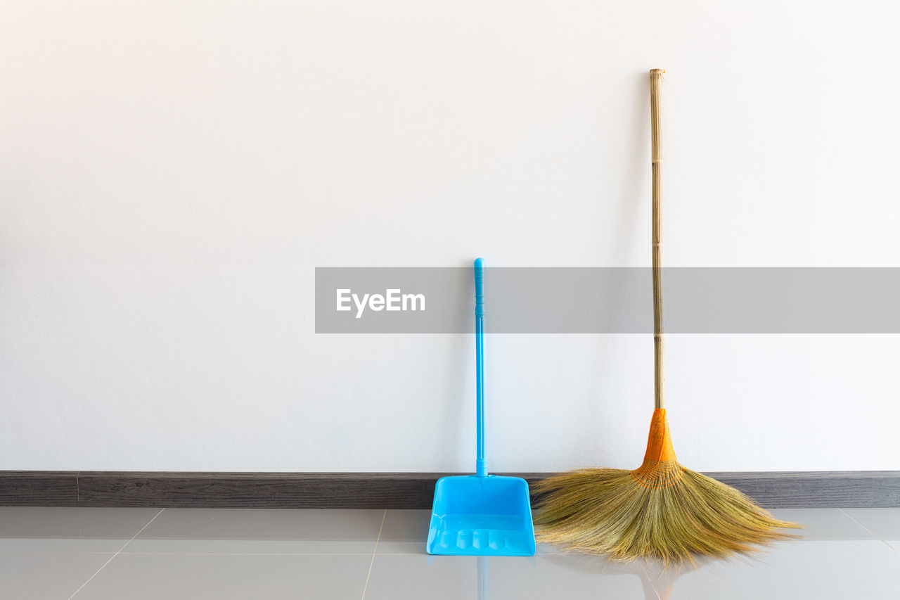 Close-up of brooms against wall at home