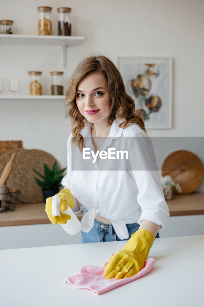 Housewife in yellow gloves wipes the kitchen table