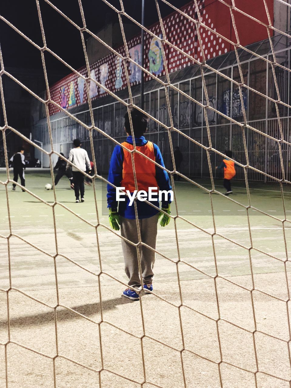 PEOPLE PLAYING SOCCER ON FIELD AGAINST SKY