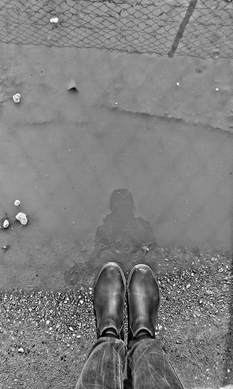 Low section view of person standing beside water puddle