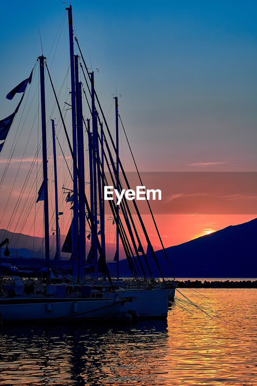 SAILBOATS MOORED IN SEA AGAINST SKY