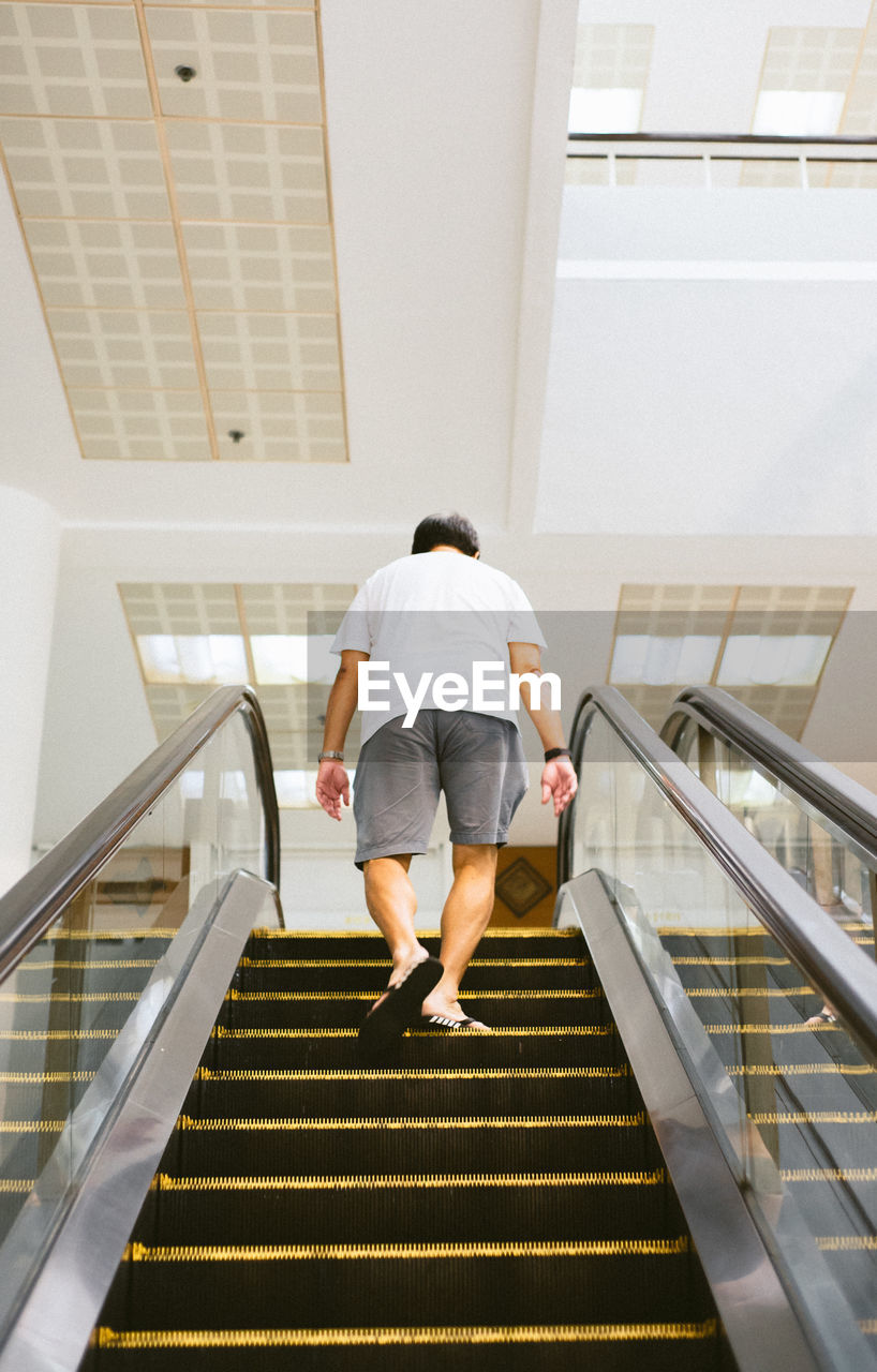 REAR VIEW OF WOMAN WALKING ON STAIRCASE