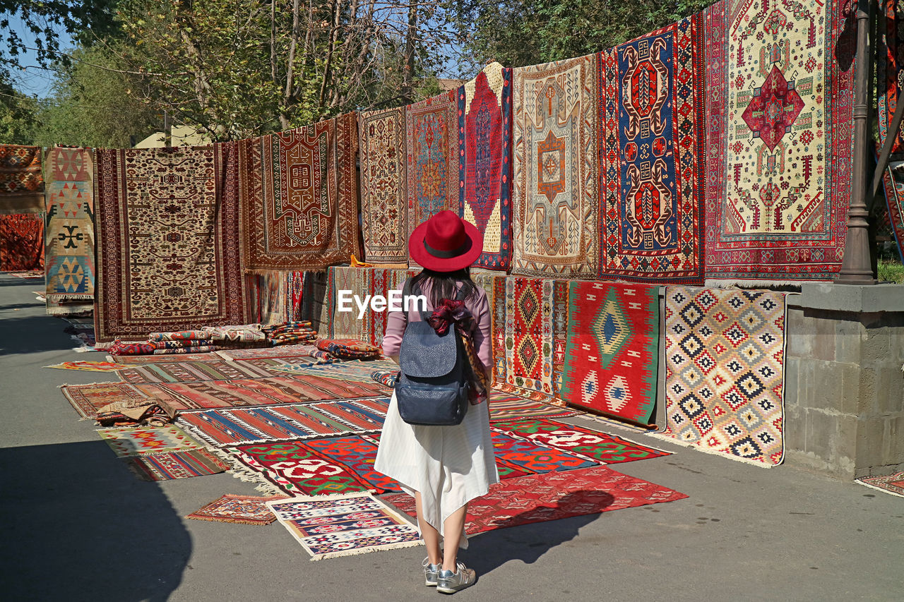 Female traveler impressed by the stunning carpets at vernissage market in downtown yerevan, armenia