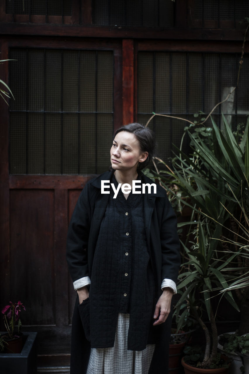 Woman looking up while standing against house 