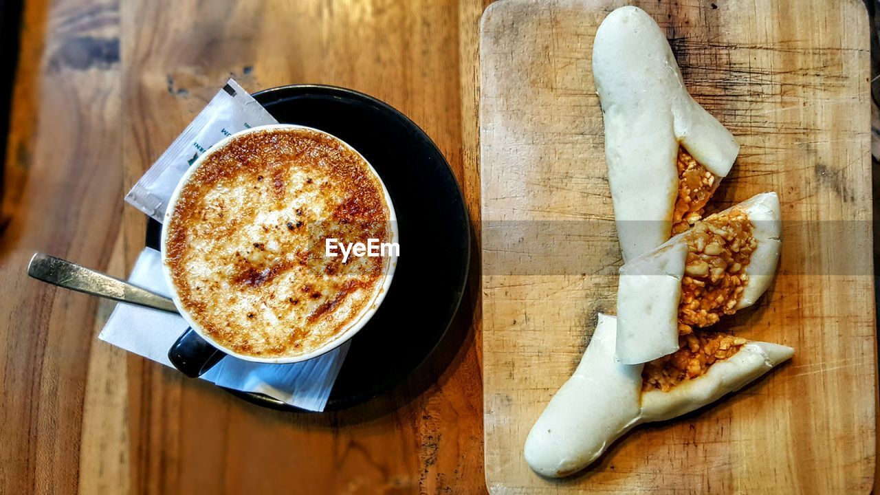 Stuffed dough roll with coffee cup on table