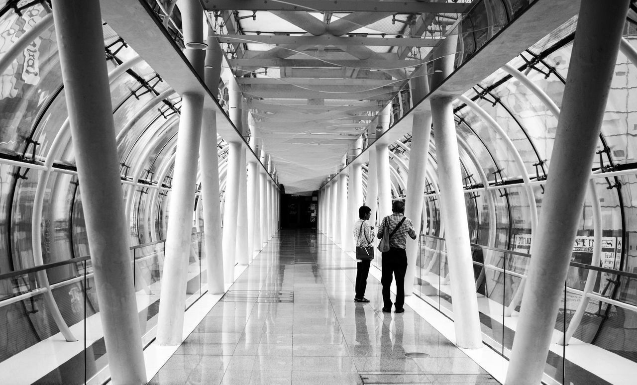 REAR VIEW OF PEOPLE WALKING IN CORRIDOR OF BUILDING