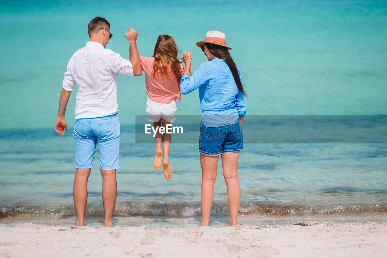 Rear view of family standing on beach