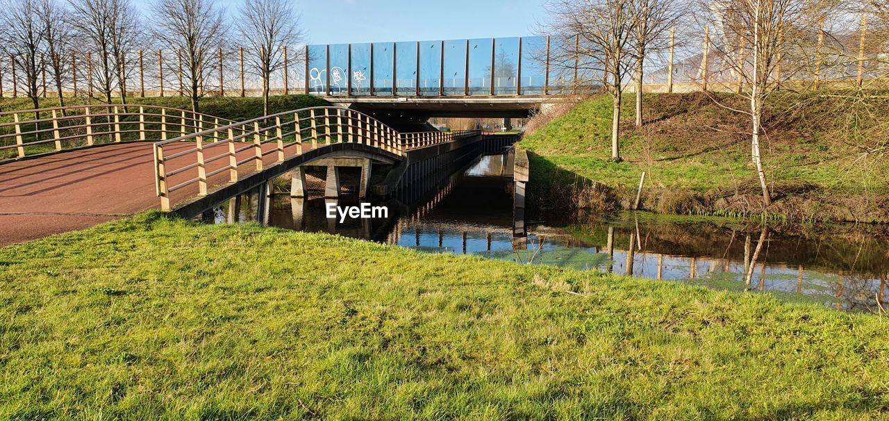 Bridge over river amidst field against sky