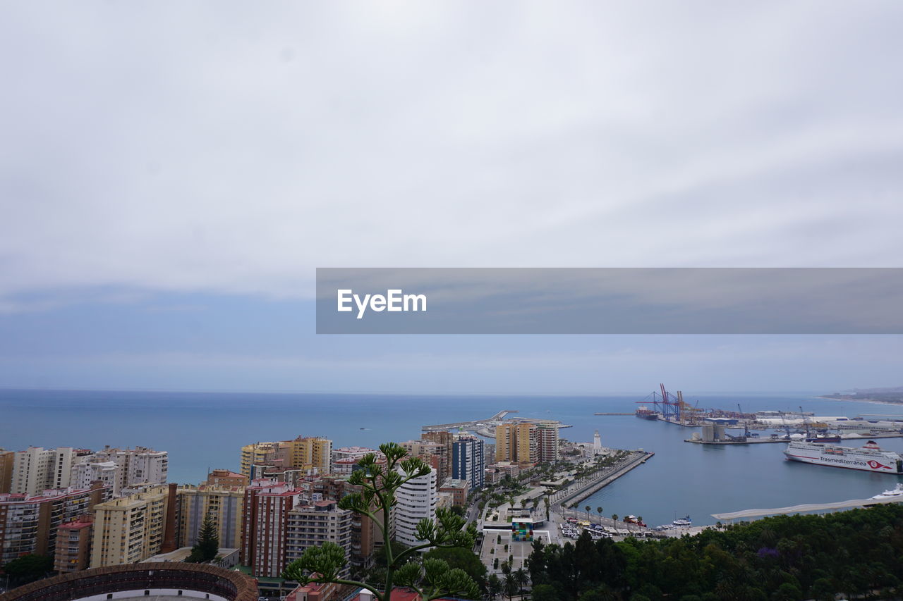 HIGH ANGLE VIEW OF CITY BUILDINGS AND BAY AGAINST SKY