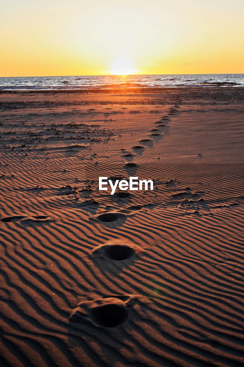 Scenic view of footprints in the sand on the beach during sunset