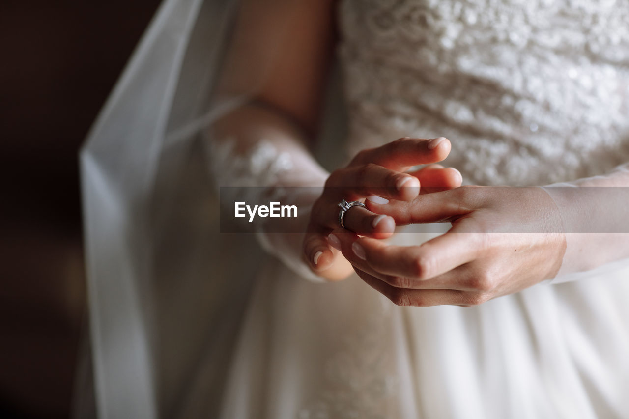 wedding dress, bride, hand, wedding, newlywed, adult, celebration, life events, women, event, love, ceremony, ring, married, positive emotion, wedding ring, dress, midsection, jewelry, indoors, holding, emotion, close-up, holding hands, one person, wedding ceremony, female, romance, focus on foreground, bridal clothing, clothing, person, white, dedication, men, tradition, beginnings